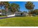 Picture-perfect front yard featuring a lush green lawn, mature palm trees, and a well-maintained, modern home at 3236 San Pedro St, Clearwater, FL 33759