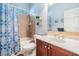 Well-lit bathroom with a shower and tub, a wooden vanity with a sink, and bright blue accents at 3727 Janus Way, Palm Harbor, FL 34685