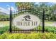 The Juniper Bay community sign features a distinctive tree logo and lush landscaping at 3727 Janus Way, Palm Harbor, FL 34685