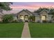 Inviting home exterior showcasing lush lawn and manicured landscaping at sunset at 3727 Janus Way, Palm Harbor, FL 34685