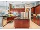 A spacious kitchen featuring stainless steel appliances, a central island, granite countertops, and dark wood cabinets at 3727 Janus Way, Palm Harbor, FL 34685