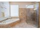 Bright bathroom featuring a soaking tub and walk-in shower with gold hardware and tiled flooring at 3727 Janus Way, Palm Harbor, FL 34685