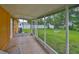 A screened-in porch overlooking a large, grassy backyard with mature trees and a fire pit at 404 12Th Sw St, Ruskin, FL 33570