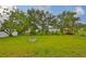 Large grassy backyard surrounded by mature trees features a fire pit at 404 12Th Sw St, Ruskin, FL 33570