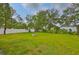 Large grassy backyard surrounded by mature trees features a fire pit at 404 12Th Sw St, Ruskin, FL 33570