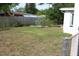 Spacious backyard with a large lawn, a wooden fence, garden beds, and plenty of room for outdoor activities at 4928 Lake Ridge Ln, Holiday, FL 34690