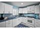 Bright kitchen with white appliances and cabinets, complemented by blue countertops and matching backsplash at 5 Gateshead Dr # 308, Dunedin, FL 34698