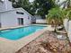 Backyard showcasing a swimming pool, patio area, landscaping, and a white fence for privacy at 6906 Shady Pl, Tampa, FL 33634