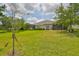 Spacious backyard with healthy lawn, scattered trees, and the home's rear exterior with screened patios at 7406 Parkshore Dr, Apollo Beach, FL 33572