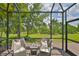 Relaxing screened-in patio with furniture and a serene view of the lush green backyard at 7406 Parkshore Dr, Apollo Beach, FL 33572