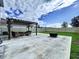 Spacious backyard featuring a concrete patio with a dark pergola, comfortable seating, and a fire pit at 7554 Wallflower Trl, Wesley Chapel, FL 33545