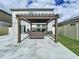 Backyard concrete patio showcasing a dark pergola, outdoor seating, and manicured green grass at 7554 Wallflower Trl, Wesley Chapel, FL 33545