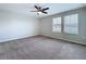 Bright, carpeted bedroom enhanced by a ceiling fan and two windows at 7554 Wallflower Trl, Wesley Chapel, FL 33545