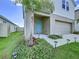 Close up of home's light blue front door with lush landscaping, solar lights, and two-car garage at 7554 Wallflower Trl, Wesley Chapel, FL 33545