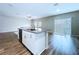 Kitchen island with stainless steel dishwasher, stylish white cabinets, and a view of the adjoining living area at 7554 Wallflower Trl, Wesley Chapel, FL 33545