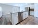 Kitchen island with stainless steel dishwasher and sink, complemented by stainless steel refrigerator and white cabinets at 7554 Wallflower Trl, Wesley Chapel, FL 33545