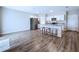 Open kitchen featuring stainless steel appliances, white cabinets, an island with seating, and wood-look floors at 7554 Wallflower Trl, Wesley Chapel, FL 33545