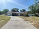 Charming single-story home with a long driveway and solar panels on a sunny day at 8209 Chaucer Dr, Weeki Wachee, FL 34607