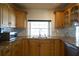 Well-lit kitchen with wood cabinets, granite countertops, double basin sink, and a view of the yard at 8209 Chaucer Dr, Weeki Wachee, FL 34607