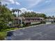 Exterior view of the condo complex with a spacious parking lot and mature palm trees at 1100 East Bay Dr # 42, Largo, FL 33770