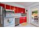 Well-lit kitchen with red cabinetry, stainless steel appliances, and bright countertops at 11104 Taft Dr, Port Richey, FL 34668