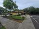 Community clubhouse with sidewalks, parking spaces, palm trees, and manicured garden and shrubbery at 11802 Raintree Lake Ln # B, Temple Terrace, FL 33617