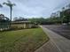 Community clubhouse featuring sidewalks, parking spaces, palm trees, and garden with manicured shrubbery at 11802 Raintree Lake Ln # B, Temple Terrace, FL 33617