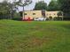 Exterior view of neutral-colored multi-story building in a residential area with a lush green lawn and three parked cars at 11802 Raintree Lake Ln # B, Temple Terrace, FL 33617