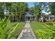 Charming blue home with a well-kept lawn and walkway framed by tropical landscaping at 1402 E Powhatan Ave, Tampa, FL 33604