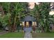 Inviting blue home with an orange door framed by lush tropical plants and a landscaped front yard at 1402 E Powhatan Ave, Tampa, FL 33604