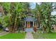 Charming two-story home featuring a blue exterior, inviting front porch, and lush tropical landscaping at 1402 E Powhatan Ave, Tampa, FL 33604