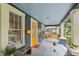 Inviting covered front porch featuring a yellow front door, swing, and ample seating area at 1402 E Powhatan Ave, Tampa, FL 33604