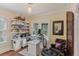 Well-lit home office with a sit-stand desk, hardwood floors, and shelves at 1402 E Powhatan Ave, Tampa, FL 33604