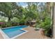 Inviting backyard pool with wooden deck surrounded by lush greenery and tropical plants for relaxing outdoors at 1402 E Powhatan Ave, Tampa, FL 33604
