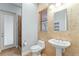 This bathroom features tan tiling, a vanity sink, a window and a shower behind a glass door at 15104 Azra Dr, Odessa, FL 33556