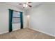 This carpeted bedroom has a ceiling fan, window with blinds and a door to the hallway at 15104 Azra Dr, Odessa, FL 33556