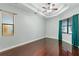 Bedroom featuring hardwood floors, a tray ceiling, a ceiling fan, and natural light from two windows at 15104 Azra Dr, Odessa, FL 33556