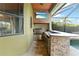 A covered outdoor kitchen features a built-in grill, sink, mini fridge, countertop, and outdoor TV at 15104 Azra Dr, Odessa, FL 33556