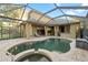 Screened-in pool area featuring travertine pavers, a lagoon-style pool with spa, and an outdoor kitchen at 15104 Azra Dr, Odessa, FL 33556