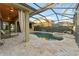 Screened-in pool area featuring travertine pavers, a lagoon-style pool with spa, and covered seating at 15104 Azra Dr, Odessa, FL 33556