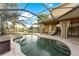 Screened-in pool area featuring travertine pavers, a lagoon-style pool with spa, and a lake view at 15104 Azra Dr, Odessa, FL 33556