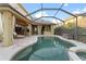 Screened-in pool area featuring travertine pavers, a lagoon-style pool with spa, and an outdoor kitchen at 15104 Azra Dr, Odessa, FL 33556