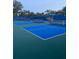 Several blue and green outdoor pickleball courts with nets and a shelter in the background at 1600 Still River Dr, Venice, FL 34293