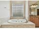 Bright bathtub with jacuzzi jets and a glass block window for natural light, set in a beige tiled surround at 21215 W Preservation N Dr, Land O Lakes, FL 34639