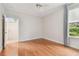 Bright bedroom featuring hardwood floors, white trim, a window with curtains, and an open door at 21215 Preservation Dr, Land O Lakes, FL 34639