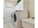 Bright laundry room with a washer, dryer, utility sink, tile floor, and overhead cabinets at 21215 W Preservation N Dr, Land O Lakes, FL 34639