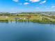 Aerial shot of waterfront home with private access to lake with lush landscaping and blue skies at 3070 Smilodon Trl, Ruskin, FL 33570