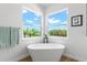 Bright bathroom featuring a standalone soaking tub with black fixtures and corner windows at 3070 Smilodon Trl, Ruskin, FL 33570