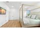 Bright bedroom featuring a four-poster bed, wood floors, and a wall-mounted TV at 3070 Smilodon Trl, Ruskin, FL 33570
