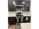 Modern kitchen showcasing stainless steel oven and microwave with dark cabinets and decorative backsplash at 3505 Gloria Ave, Plant City, FL 33563